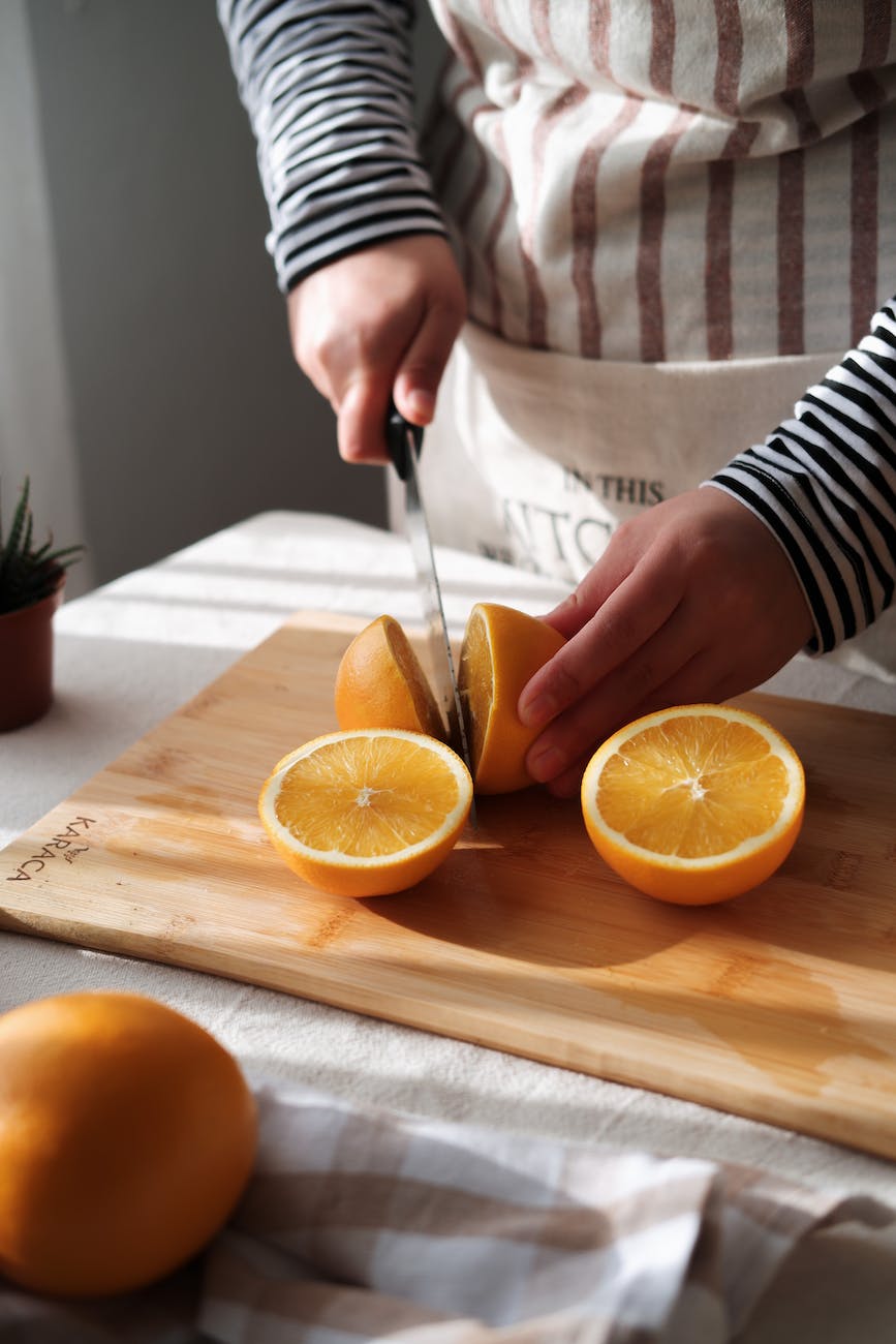 hand cutting oranges on cutting board