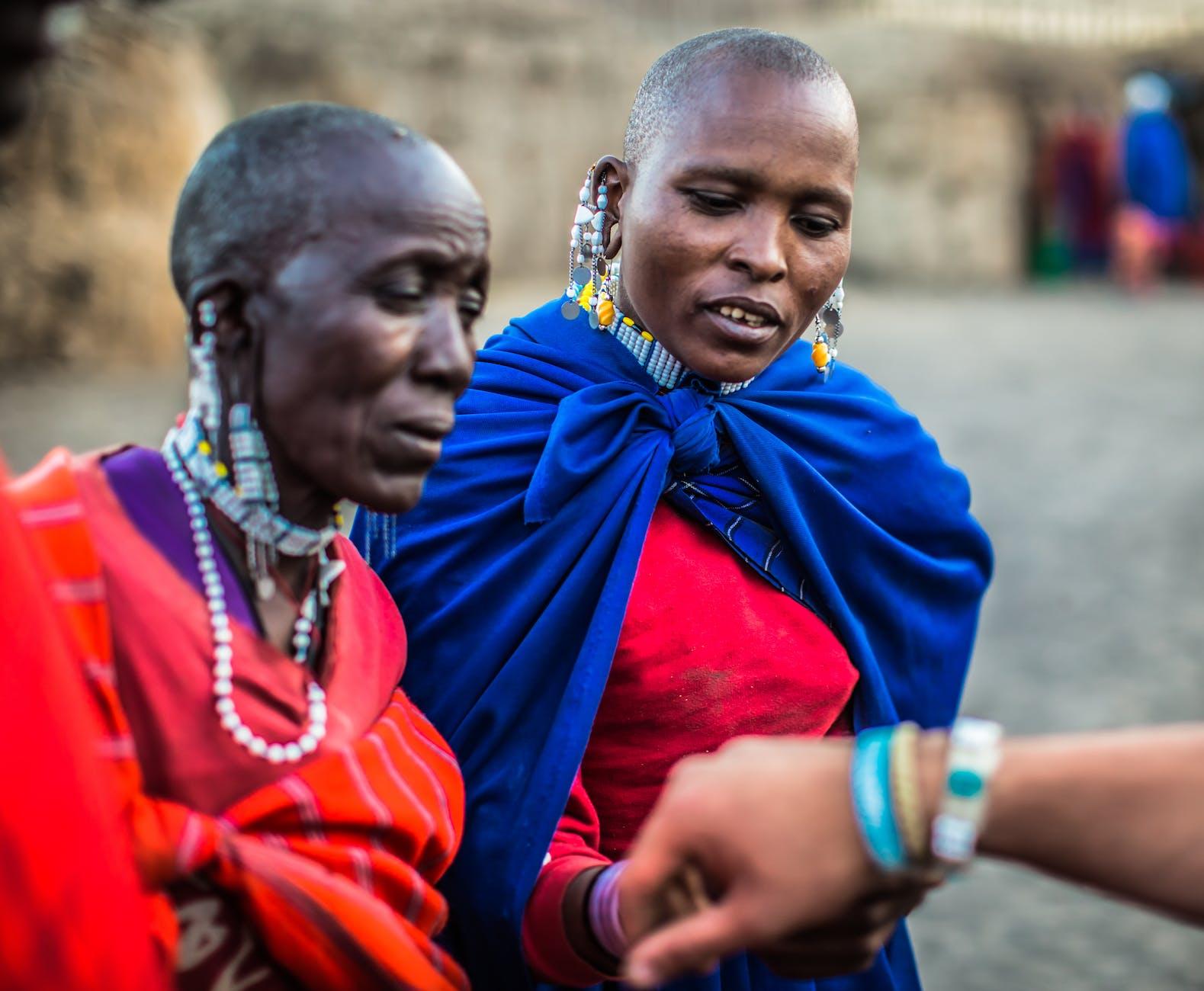 two woman looking on persons bracelet