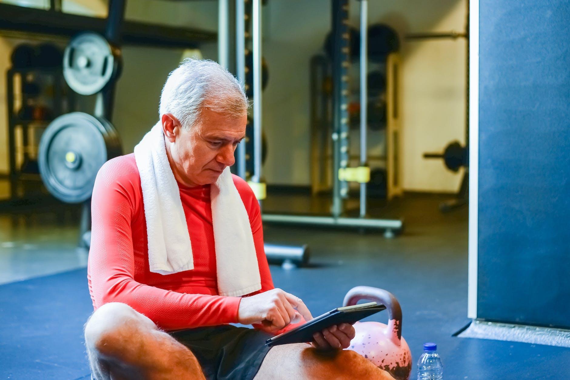 an elderly man in red long sleeves using his tablet