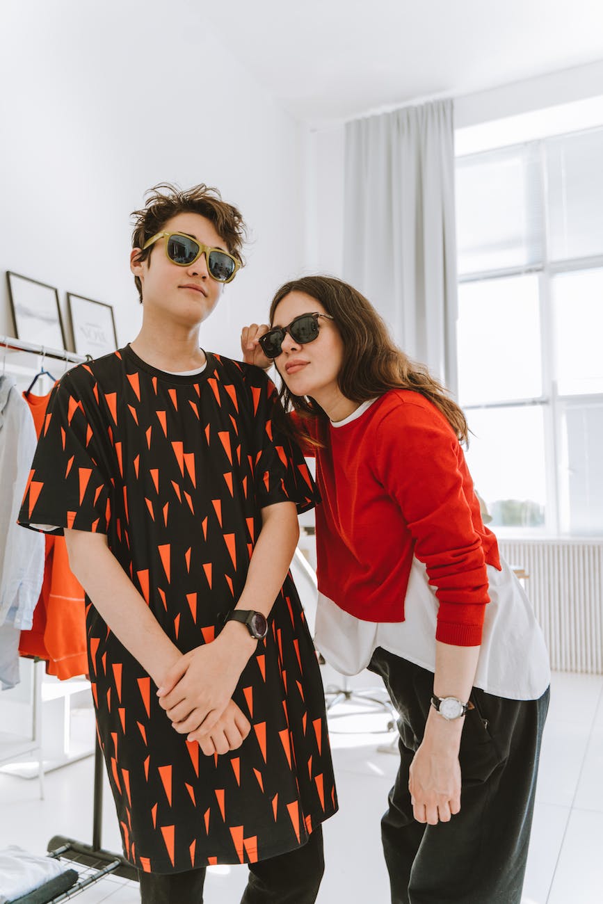 a young boy standing next to his mother in red long sleeves