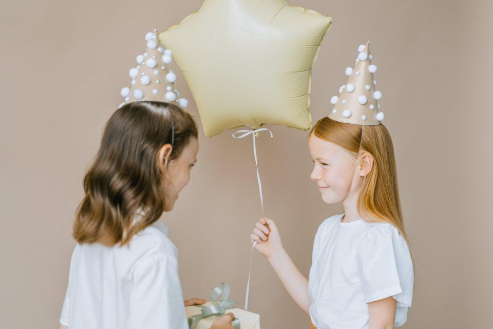 photo of a girl holding a balloon near another girl