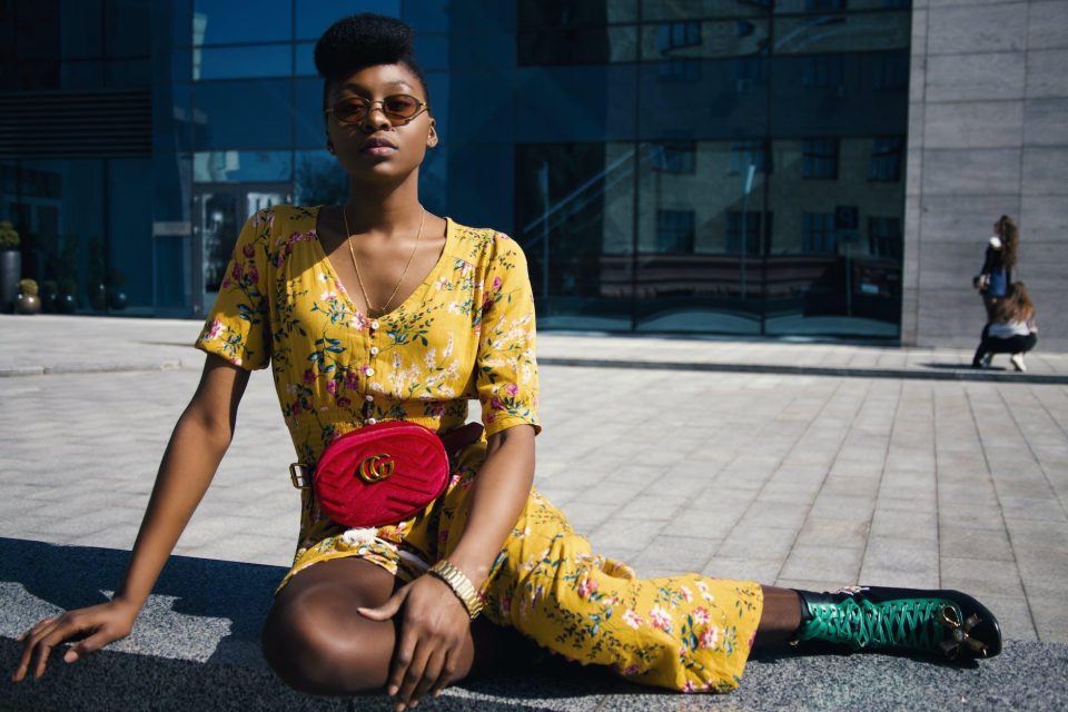 woman in yellow floral jumpsuit sitting on concrete floor