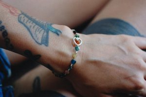 a tattooed person wearing a colorful beaded bracelet