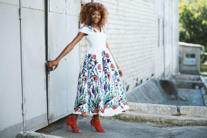 woman in white and multicolored midi dress holding door